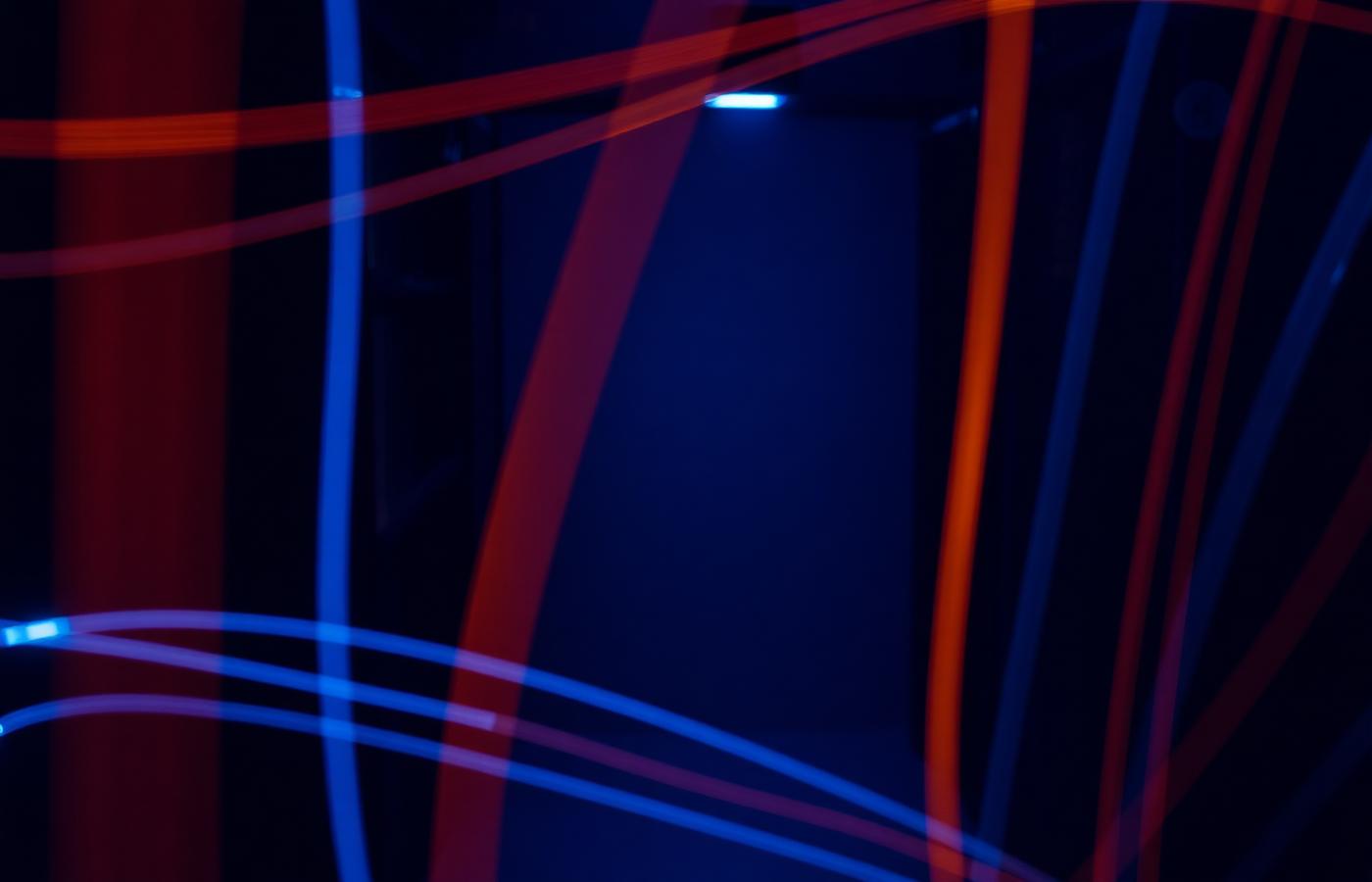 Long exposure light trails in red and blue across a dark studio